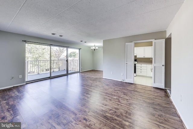 empty room with a chandelier and dark hardwood / wood-style floors