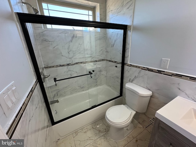 full bathroom featuring tile walls, vanity, shower / bath combination with glass door, and toilet