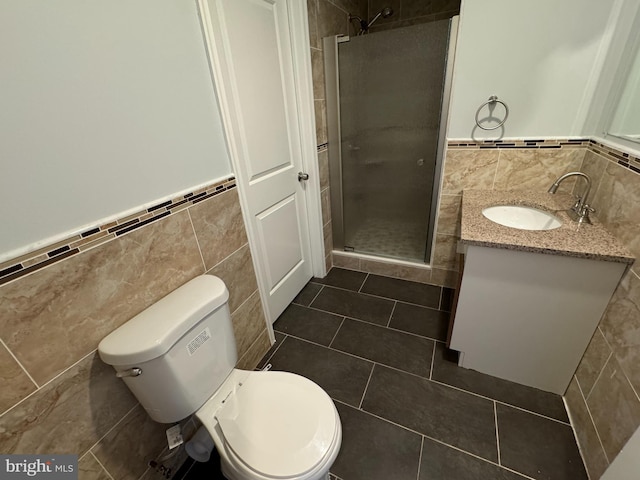 bathroom with an enclosed shower, toilet, tile patterned floors, tile walls, and vanity