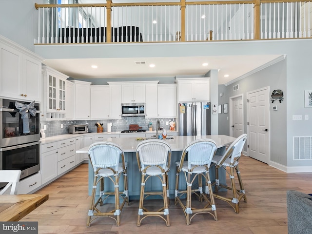 30579 Canary Way Unit 5, Ocean View, DE 19970 - kitchen featuring appliances with stainless steel finishes, light countertops, light wood-type flooring, a towering ceiling, and crown molding