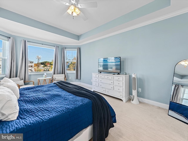 carpeted bedroom with multiple windows, a raised ceiling, and ceiling fan