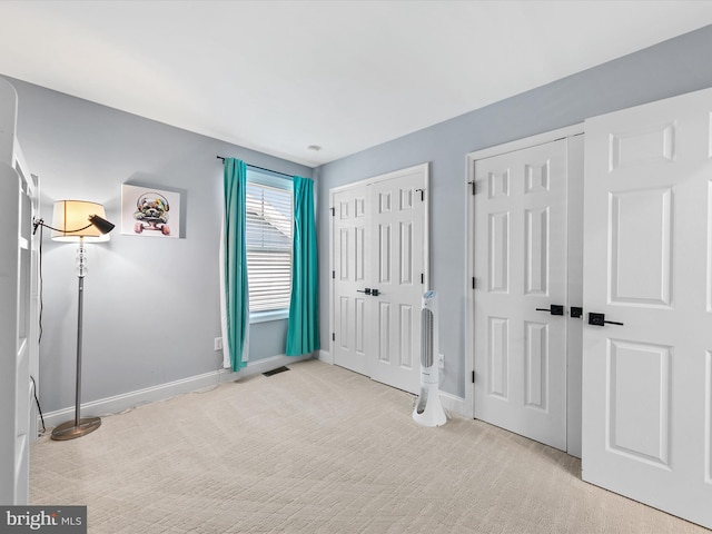 unfurnished bedroom featuring two closets and light colored carpet