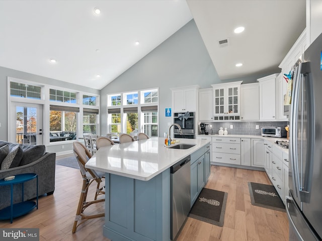 kitchen featuring appliances with stainless steel finishes, white cabinetry, a kitchen bar, light hardwood / wood-style floors, and sink