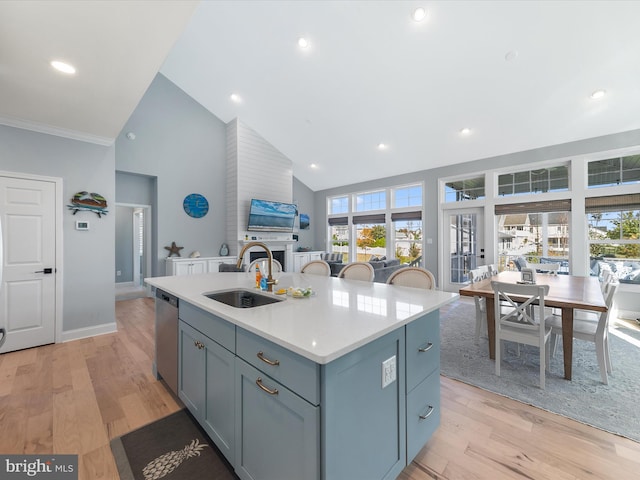 kitchen with sink, dishwasher, light hardwood / wood-style floors, high vaulted ceiling, and a center island with sink