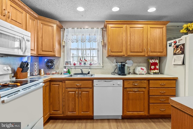 kitchen featuring light hardwood / wood-style floors, a textured ceiling, sink, and white appliances