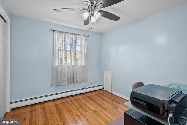 misc room with a baseboard radiator, light hardwood / wood-style floors, and ceiling fan