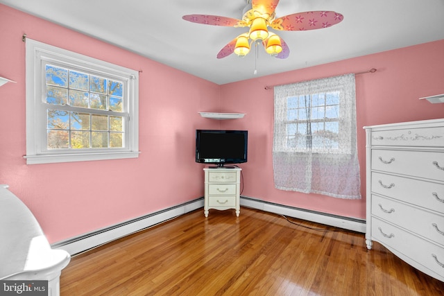 bedroom with multiple windows, a baseboard radiator, and light wood-type flooring