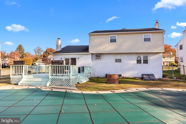 rear view of house with a swimming pool side deck and a lawn