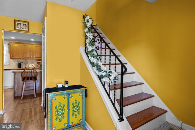 staircase with bar area and hardwood / wood-style flooring