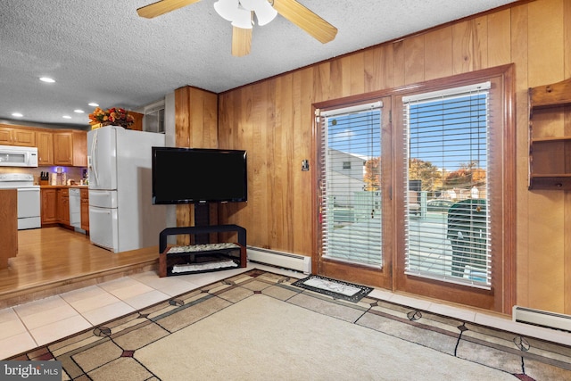 tiled living room featuring ceiling fan, a healthy amount of sunlight, a textured ceiling, and wooden walls