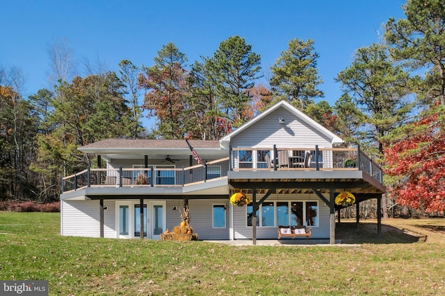 rear view of property featuring a lawn, ceiling fan, a wooden deck, and a patio