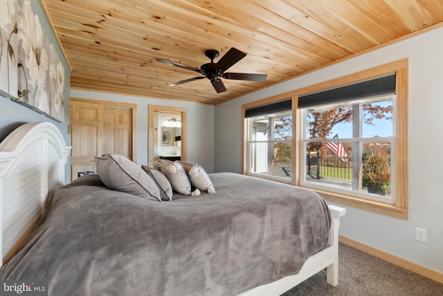 carpeted bedroom featuring wooden ceiling, ceiling fan, ensuite bath, and a closet