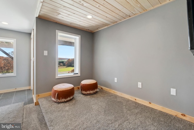 sitting room featuring dark colored carpet and wooden ceiling