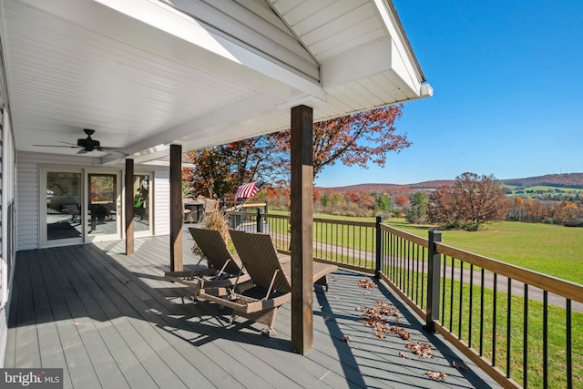 wooden terrace with a mountain view, ceiling fan, and a yard