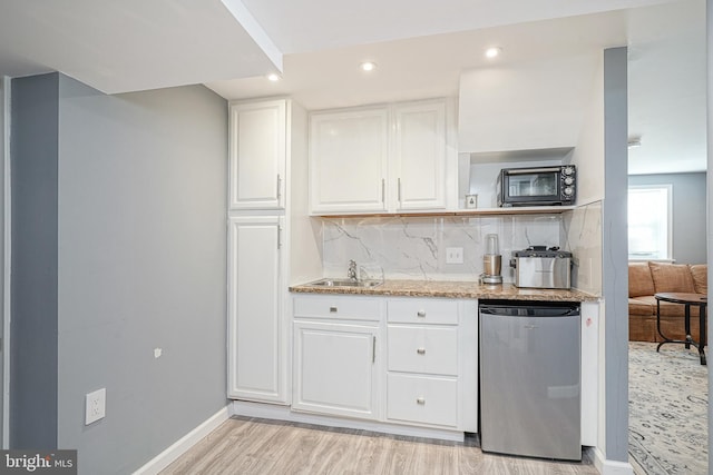 kitchen with white cabinetry, sink, stainless steel dishwasher, light wood-type flooring, and decorative backsplash