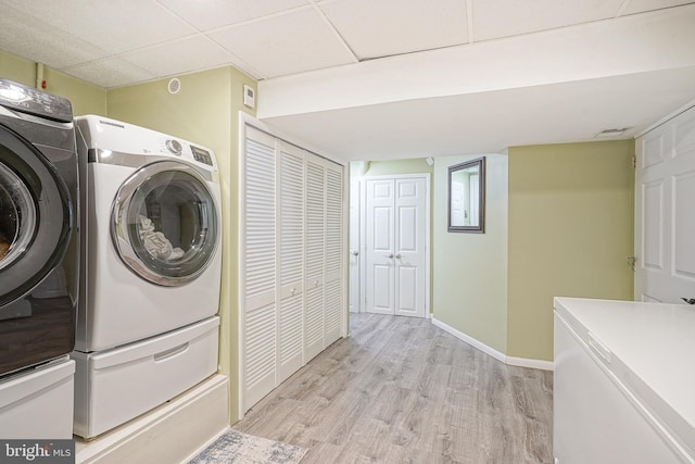 clothes washing area featuring washing machine and dryer and light wood-type flooring