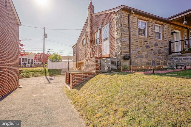 view of side of home with cooling unit and a yard