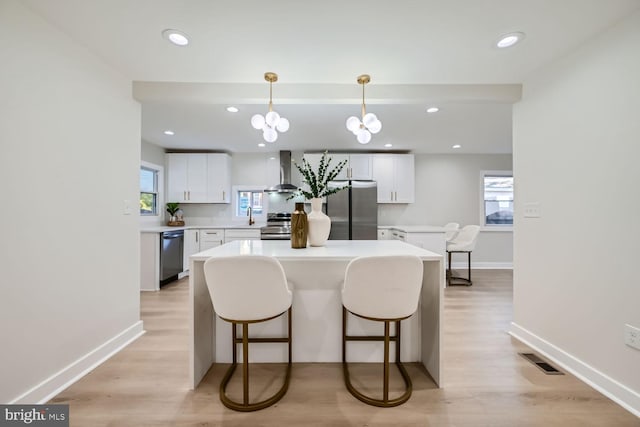 kitchen with white cabinetry, pendant lighting, stainless steel appliances, and light wood-type flooring