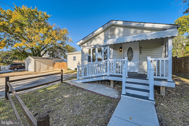 bungalow-style home with covered porch and a storage shed