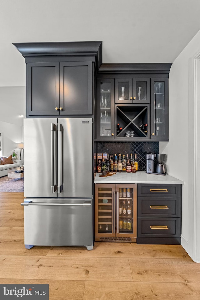 bar with wine cooler, tasteful backsplash, light hardwood / wood-style flooring, and high quality fridge