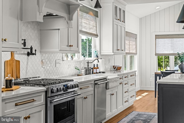 kitchen with appliances with stainless steel finishes, light hardwood / wood-style flooring, white cabinetry, and tasteful backsplash