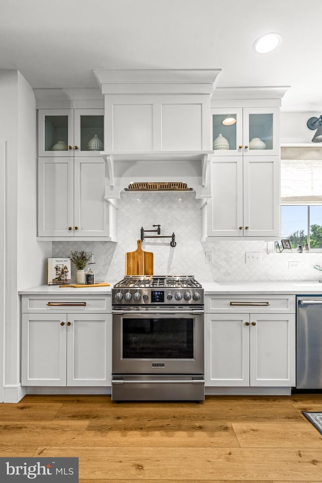 kitchen featuring white cabinetry, light hardwood / wood-style floors, appliances with stainless steel finishes, and decorative backsplash