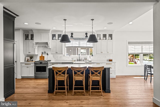 kitchen with white cabinetry, gas stove, tasteful backsplash, and light wood-type flooring