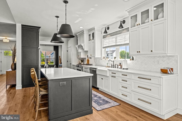 kitchen featuring stainless steel appliances, sink, a center island, pendant lighting, and light hardwood / wood-style floors