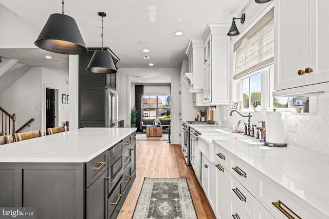 kitchen with light hardwood / wood-style flooring, a wealth of natural light, decorative light fixtures, white cabinetry, and tasteful backsplash