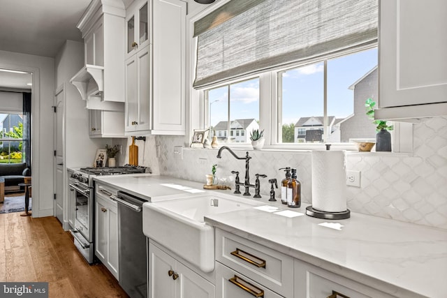 kitchen featuring tasteful backsplash, light stone countertops, appliances with stainless steel finishes, dark hardwood / wood-style flooring, and white cabinetry