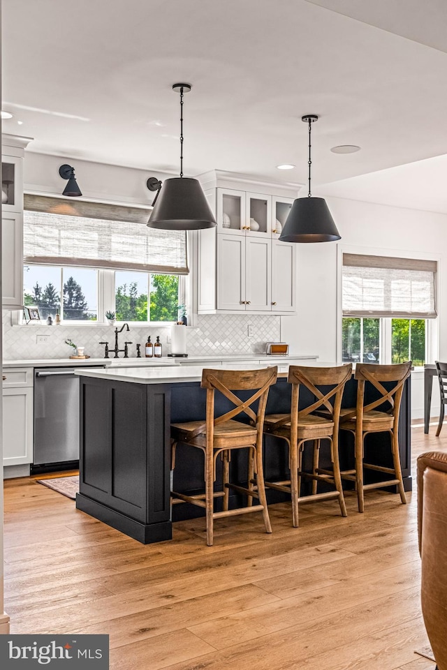 kitchen with white cabinetry, dishwasher, light hardwood / wood-style floors, decorative light fixtures, and a center island