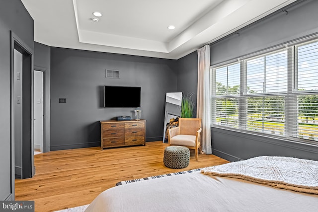 bedroom featuring light hardwood / wood-style flooring and a raised ceiling