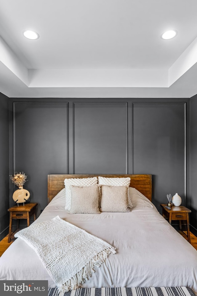 bedroom featuring hardwood / wood-style flooring and a tray ceiling