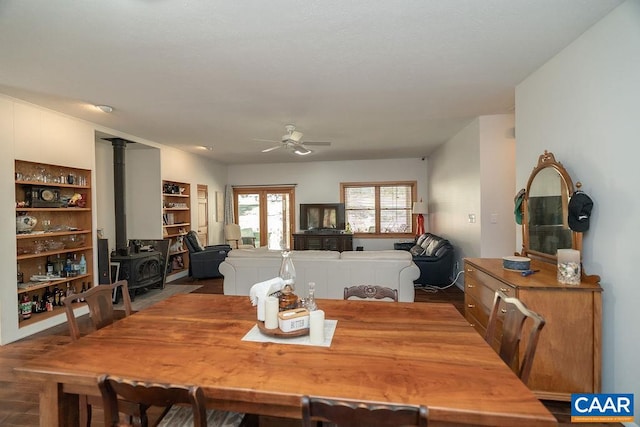 dining room with a wood stove, hardwood / wood-style flooring, and ceiling fan