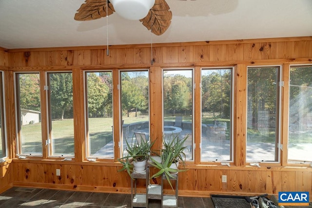 unfurnished sunroom featuring ceiling fan and a wealth of natural light