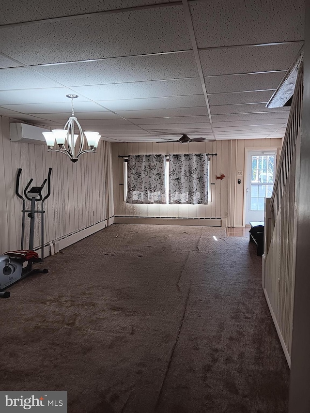 interior space featuring carpet, a paneled ceiling, an inviting chandelier, and wooden walls