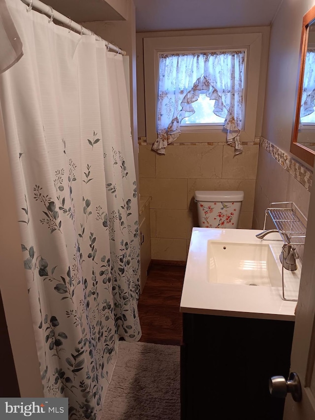 bathroom with hardwood / wood-style floors, tile walls, toilet, vanity, and a shower with shower curtain