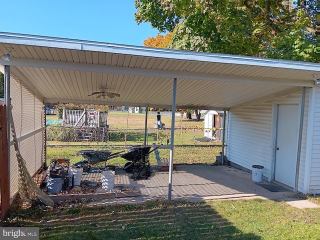 view of vehicle parking featuring ceiling fan, a lawn, and a carport