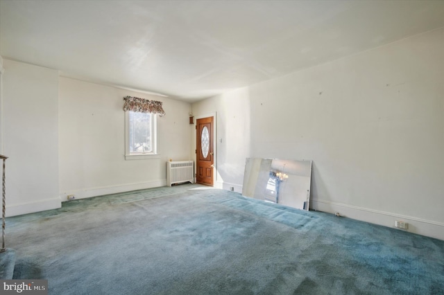 spare room featuring light carpet and radiator