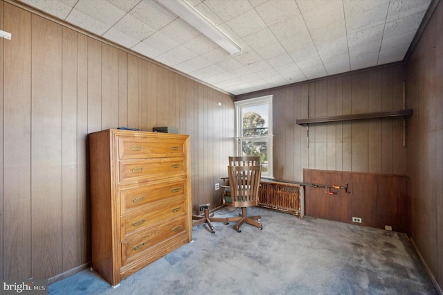 sitting room featuring wooden walls and light colored carpet