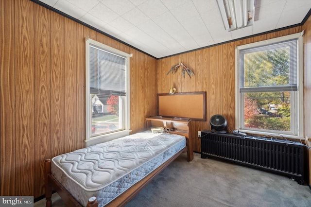 carpeted bedroom featuring wood walls and radiator