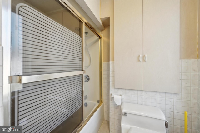 bathroom featuring tile walls, enclosed tub / shower combo, and toilet