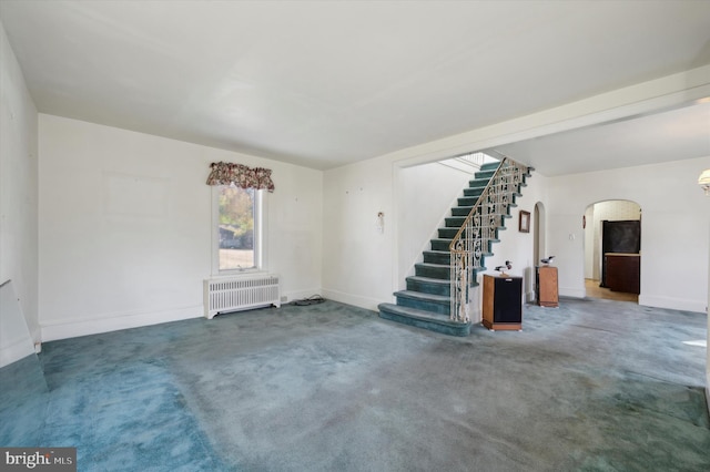 unfurnished living room featuring carpet flooring and radiator heating unit