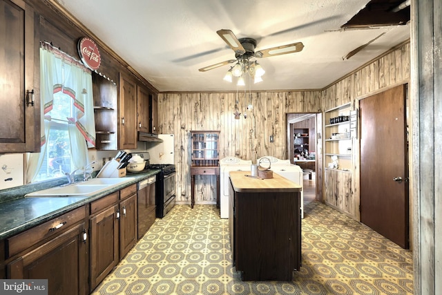 kitchen featuring a kitchen island, butcher block counters, wooden walls, sink, and black gas range oven