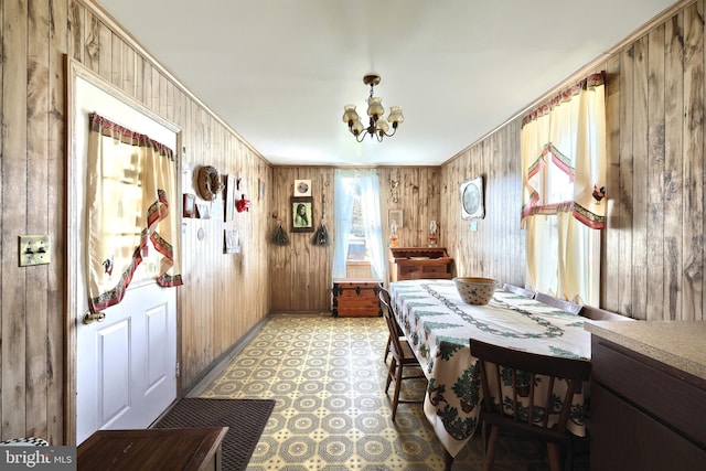 dining area featuring a notable chandelier and wood walls