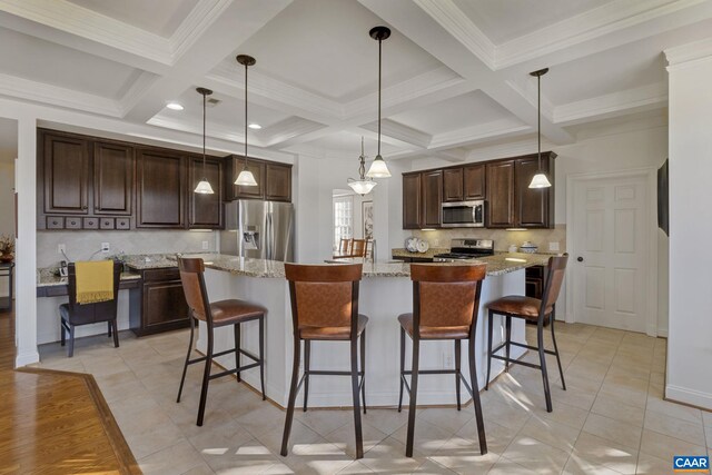 kitchen featuring light stone countertops, stainless steel appliances, pendant lighting, beam ceiling, and a center island with sink