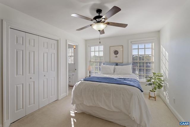 bedroom featuring a closet, ensuite bath, light colored carpet, and ceiling fan