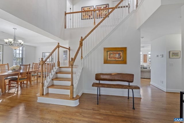 staircase featuring hardwood / wood-style flooring, a high ceiling, and a chandelier