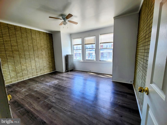 spare room with dark wood-type flooring, ceiling fan, crown molding, and radiator