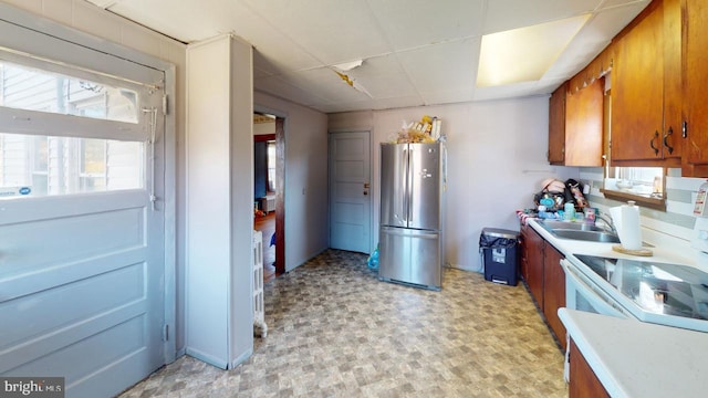 kitchen featuring white electric range oven, stainless steel fridge, and sink